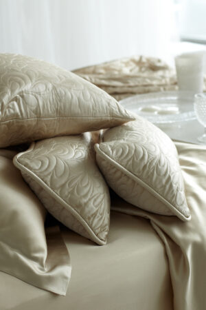 Elegant quilted silk pillows on a silk sheet, showcasing intricate stitching and luxurious texture.