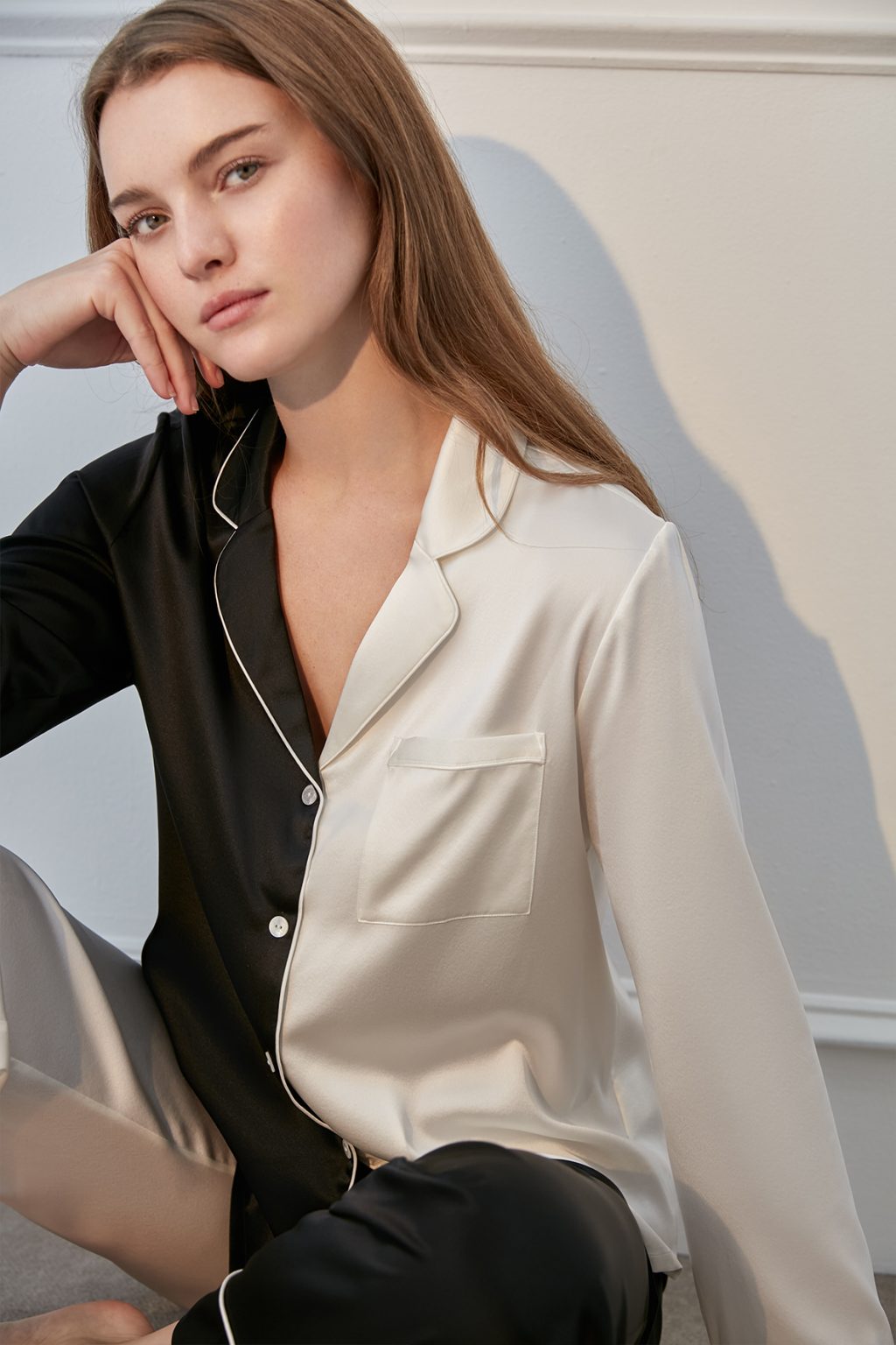 Woman in elegant Contrast Silk Pajama Set with black and cream colors.