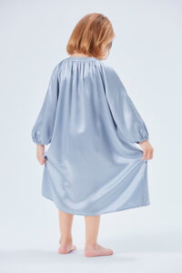Young girl in a flowing crystal blue silk nightgown from behind.