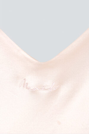 Close-up of the basal round-neck silk nightdress showing the embroidered brand name "MANITO".