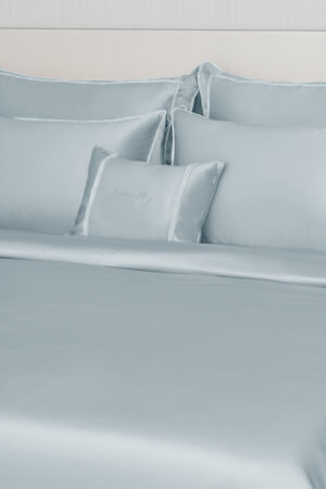 Close-up of MANITO Fringe Silk Duvet Cover with white fringe trims, highlighting the silky texture and elegant pillow arrangement.