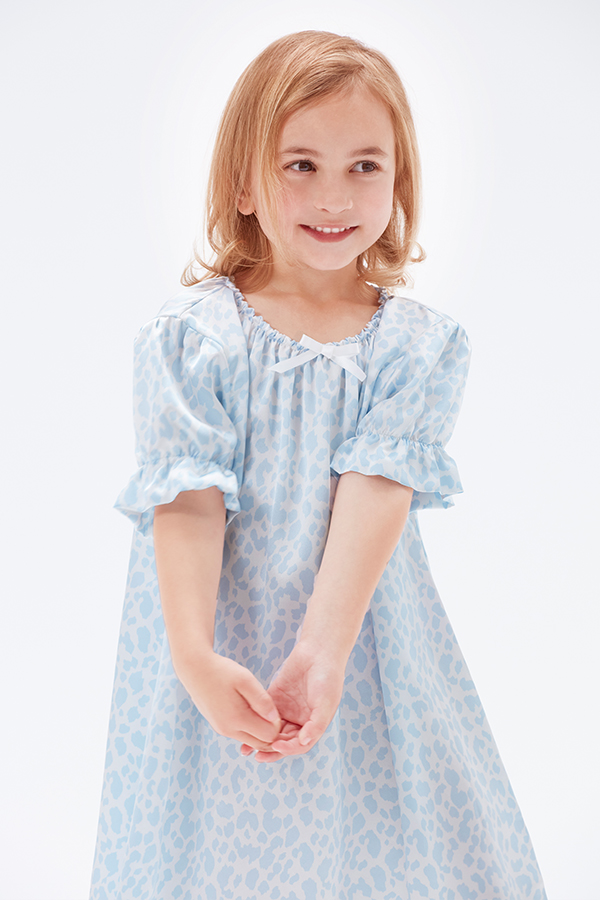Smiling little girl in a blue leopard print silk nightgow.