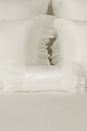 Close-up of Moonlight silk bedding with embroidered bolster and lace-trimmed pillowcases, highlighting ethereal softness.