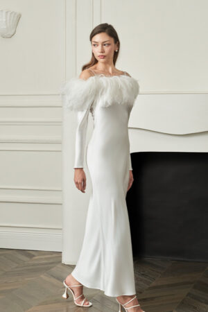Woman walks in white New Diva Feather Off-the-shoulder Dress, slim silhouette and refined neckline moving gracefully with each step.