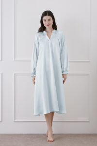 Front view of woman in baby blue midi dress, showcasing V-neck, ruffle trim, and lantern sleeves, combining comfort and elegance.