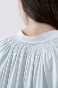 Close-up of MANITO logo embroidery detail on back of Sophia midi dress, showcasing intricate craftsmanship.