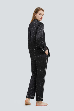 Back view of a woman showcasing the Signature Women's Pajama Set with detailed piping and print on a black fabric.