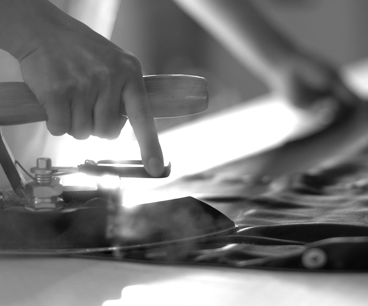 Artisan's hands using traditional tools for silk finishing, reflecting MANITO's commitment to craftsmanship.