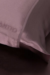 Close-up of The 22 Silk Pillowcase Set in plum purple color with embroidered logo of MANITO.