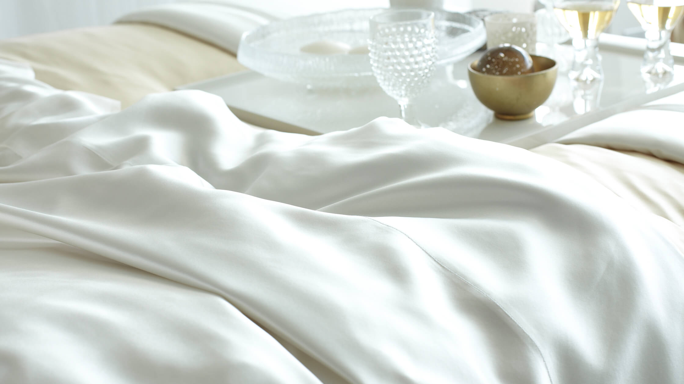 Pristine white silk sheets on bed with potential for easy cleaning of stains, including blood removal.